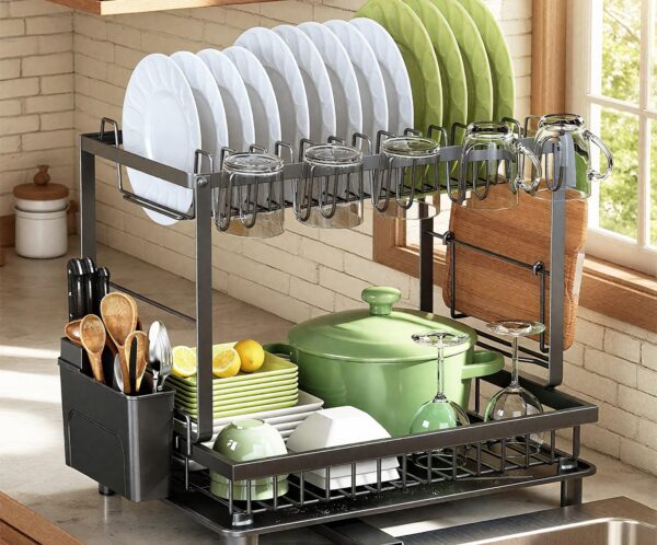 Dish drying rack with white and green plates, mugs, and glassware drying over a kitchen sink area.