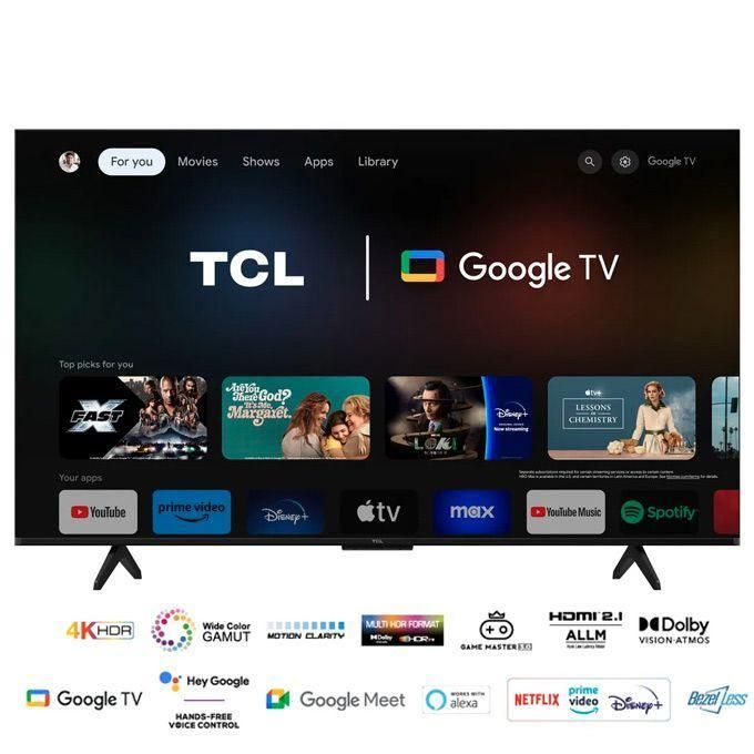TCL Google TV on a stand showing the home screen with a dark background, navigation menu, and a row of app thumbnails beneath the main banner (YouTube, Prime Video, Disney+, Apple TV, Max, Spotify).