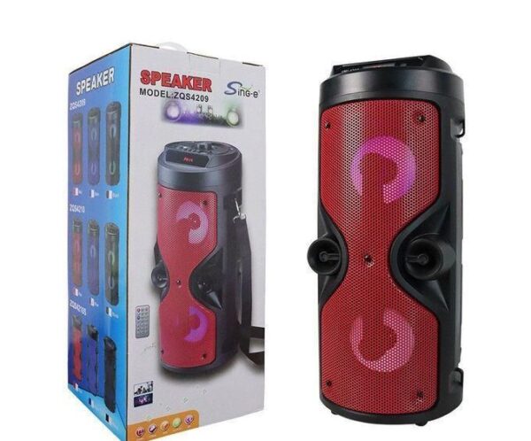 Red portable Bluetooth speaker with two round drivers, shown beside its packaging box.