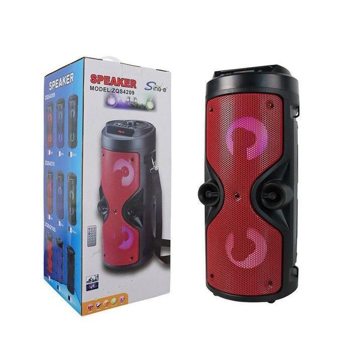 Red portable Bluetooth speaker with two round drivers, shown beside its packaging box.
