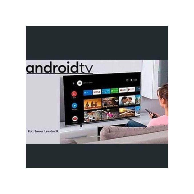 Person lounging on a sofa using a remote to navigate an Android TV interface on a wall-mounted TV.