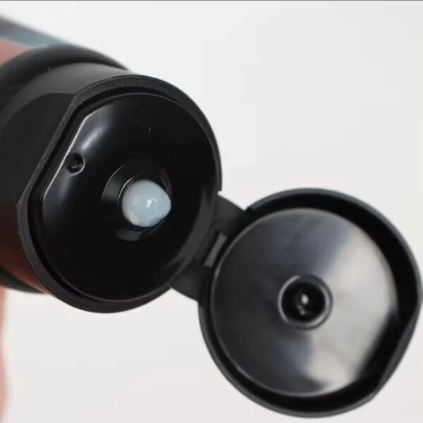 Close-up of a black flip-top bottle cap opened, exposing the inner seal and small nozzle.
