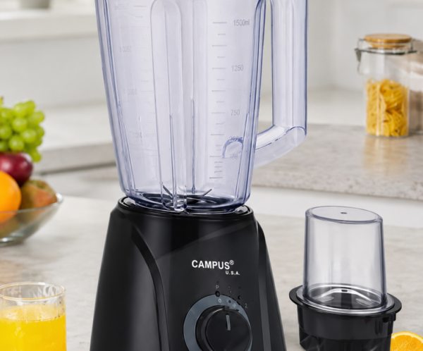 Black Campus USA blender with large transparent pitcher and lid on a kitchen counter; juice and fruit nearby, plus a separate blending cup on the side.