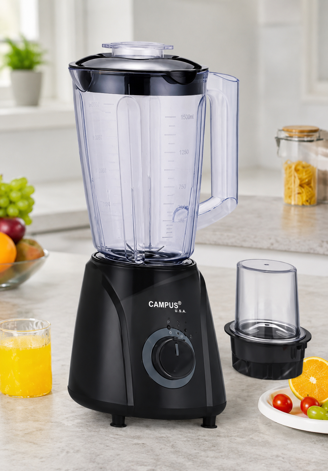 Black Campus USA blender with large transparent pitcher and lid on a kitchen counter; juice and fruit nearby, plus a separate blending cup on the side.