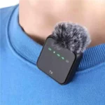 Clipped-on wireless lavalier microphone with a furry windscreen resting on a blue sweater near the neck.