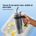 One-handed, stable grip on a grey insulated tumbler with a black handle and straw, held above a cooler with ice and lemon slices.