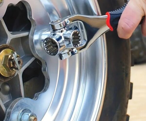 Close-up of a person using a chrome socket wrench to tighten lug nuts on a motorcycle wheel rim.