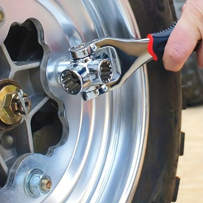 Close-up of a person using a chrome socket wrench to tighten lug nuts on a motorcycle wheel rim.