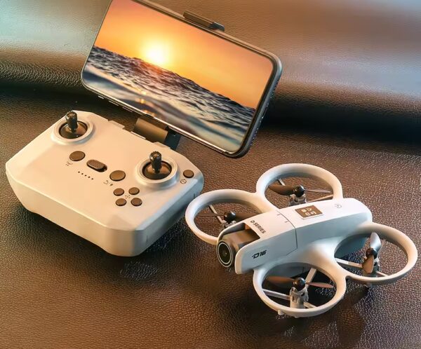 Quadcopter with prop guards beside a white remote, phone mounted showing a sunset over ocean for live drone feed