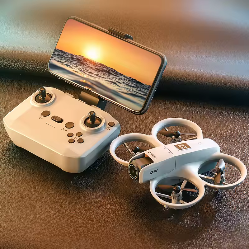 Quadcopter with prop guards beside a white remote, phone mounted showing a sunset over ocean for live drone feed